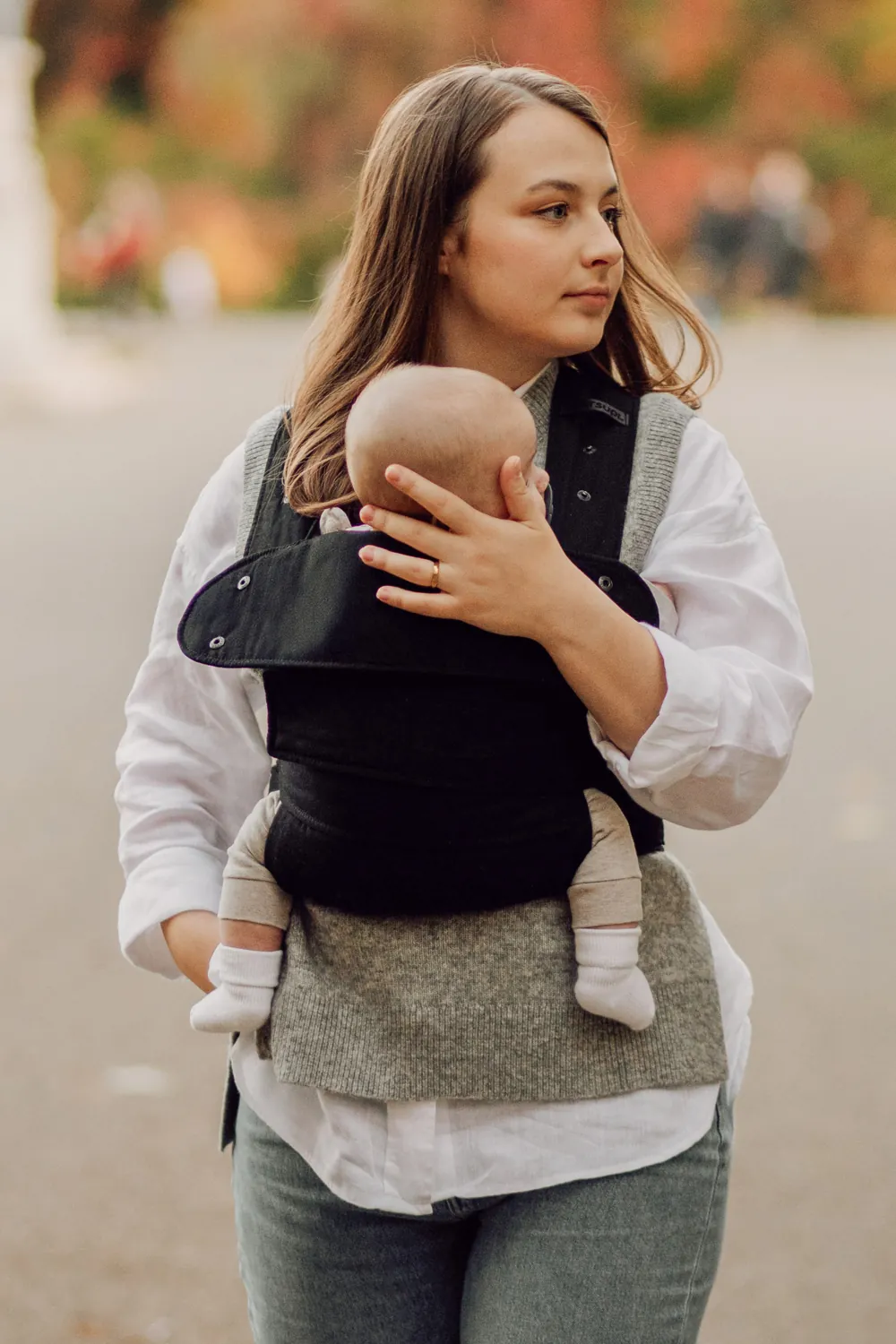 Mama trägt Baby draußen in Marsupi Classic Babytrage Schwarz.