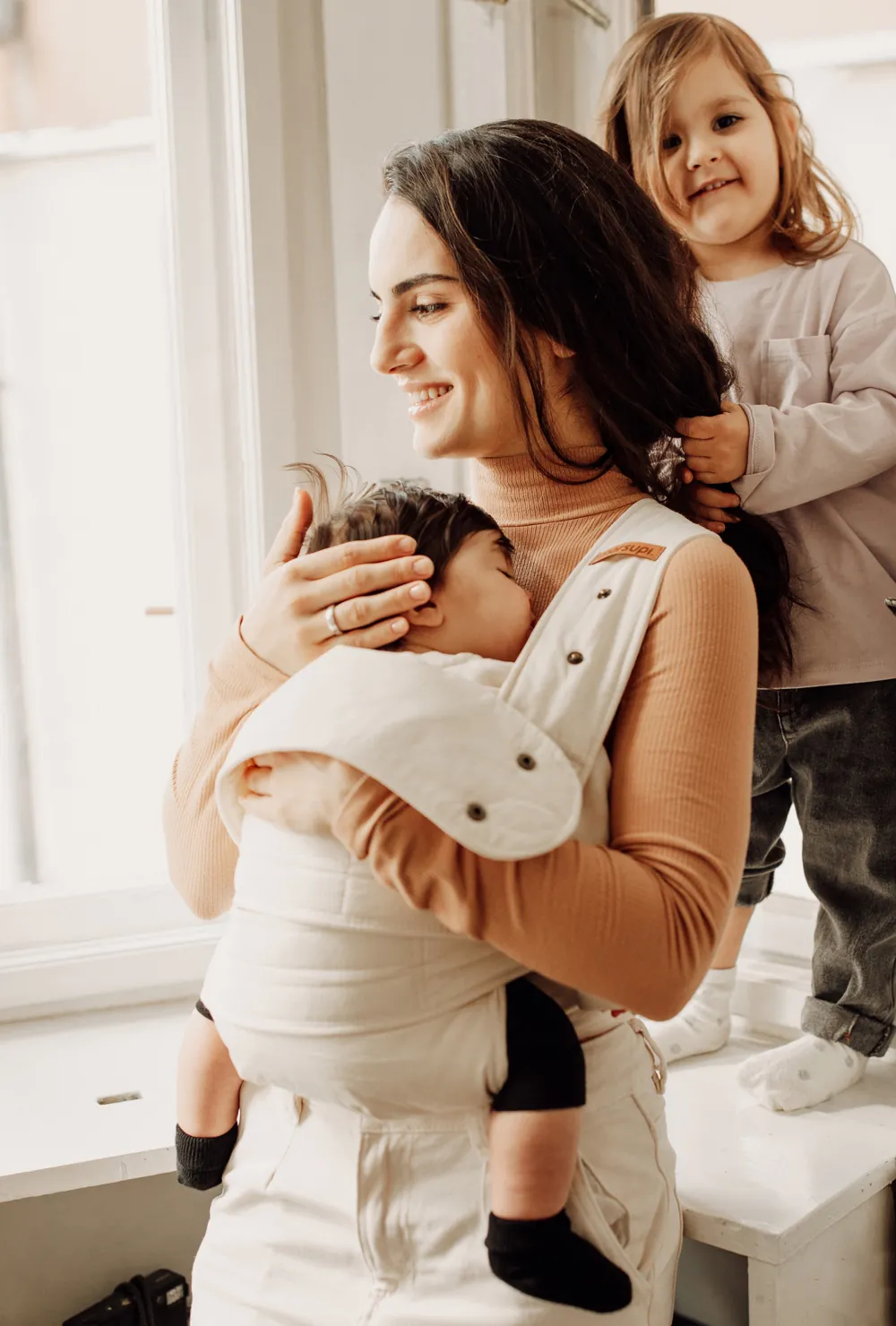 Studiofoto: Frau trägt Baby in Marsupi Classic 2 Babytrage Natural in Seitenansicht