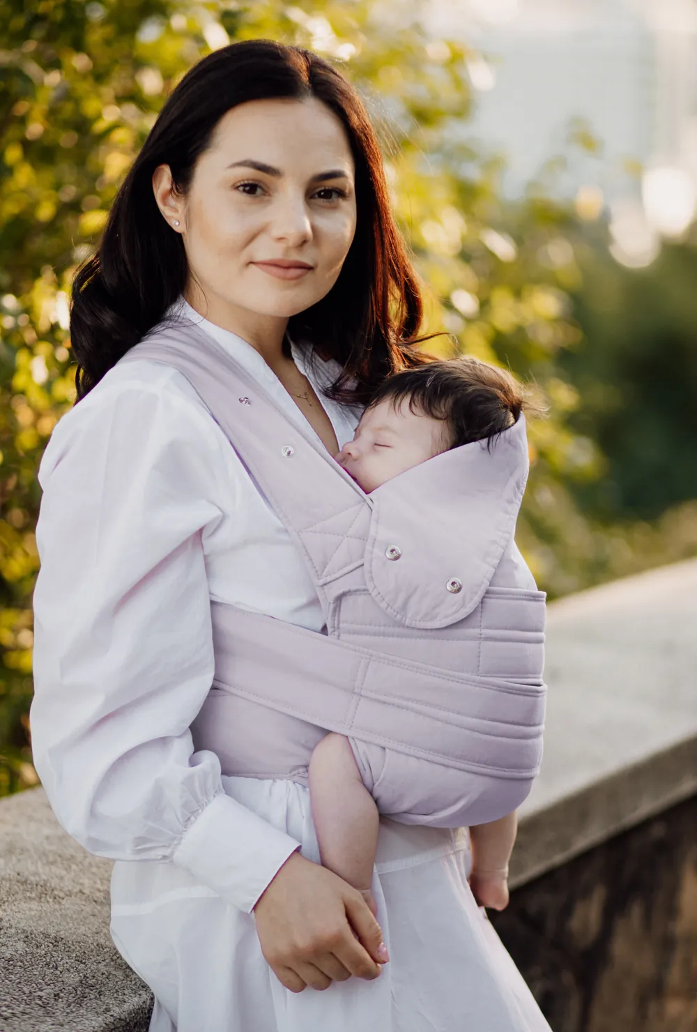 Frau trägt Baby in der marsupi breeze Babytrage in Lilac, Outdoor-Aufnahme am Geländer