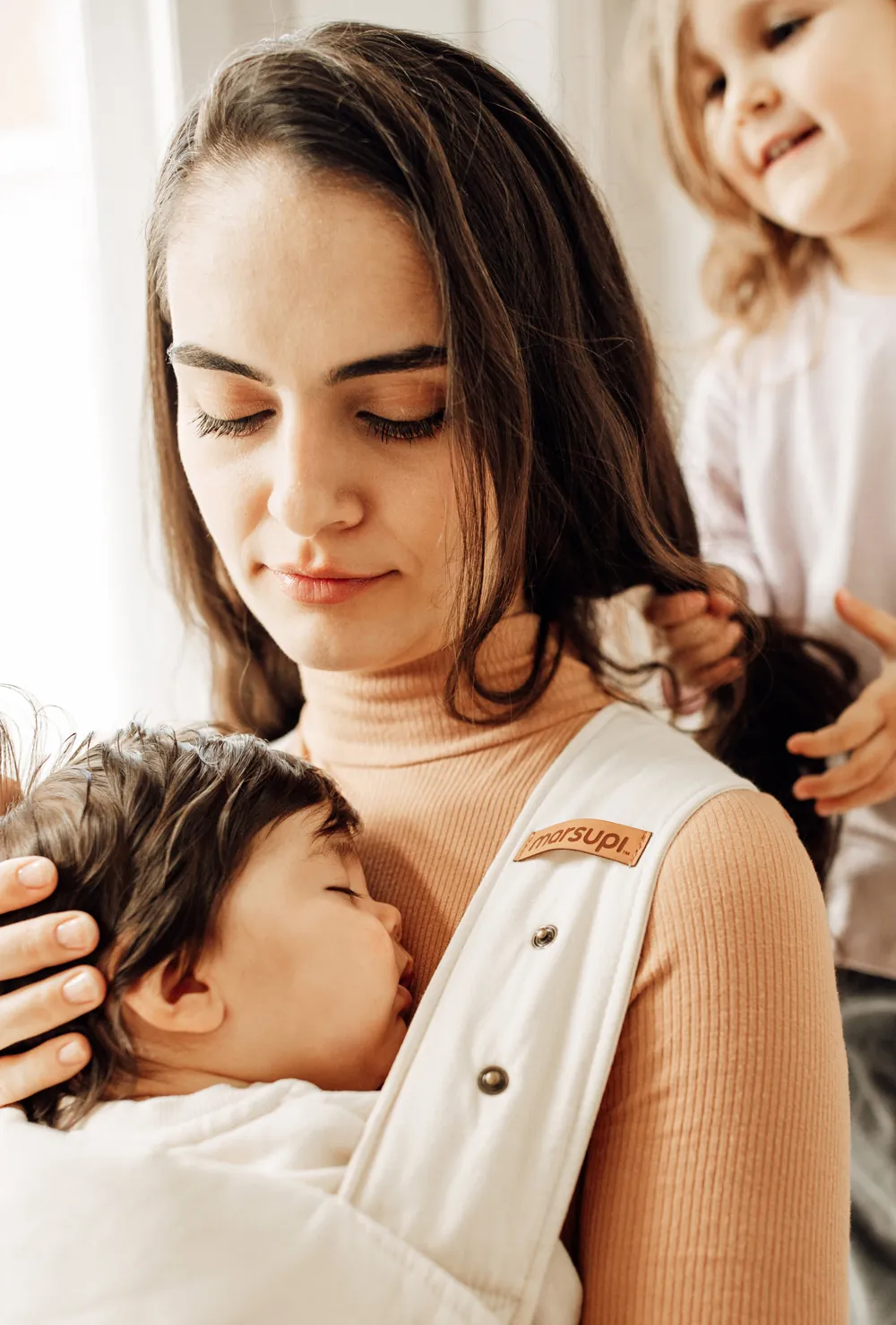 Nahaufnahme: Mutter hält Baby in Marsupi Classic 2 Babytrage Natural, Kleinkind greift nach ihren Haaren