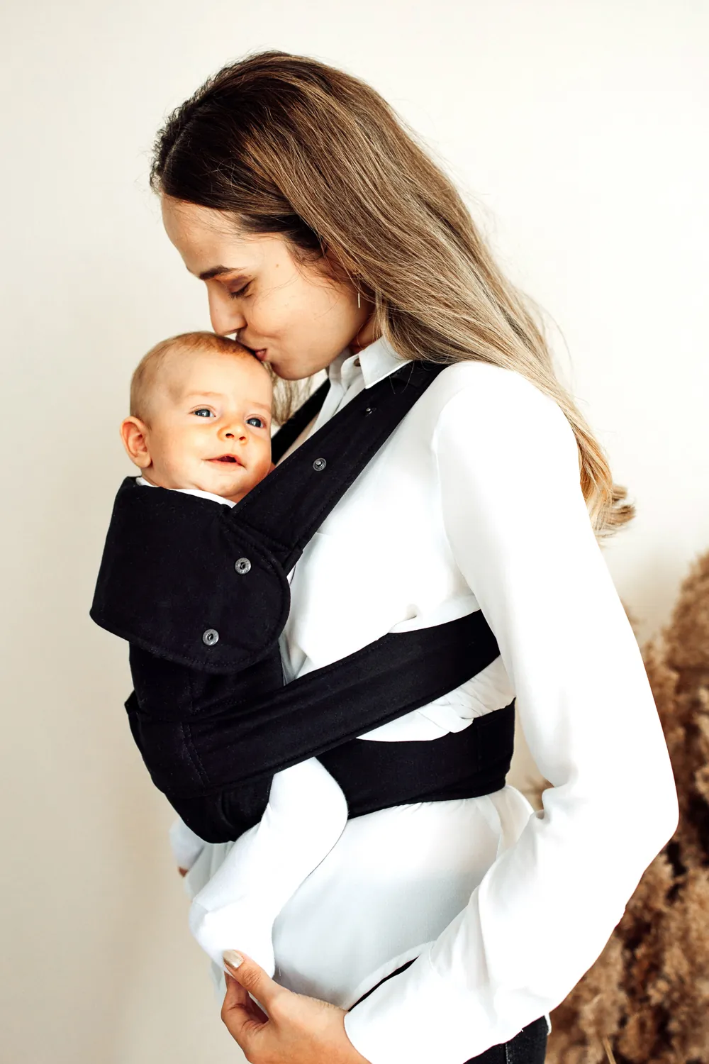 Mama küsst Baby, getragen in Marsupi Classic Babytrage Schwarz.