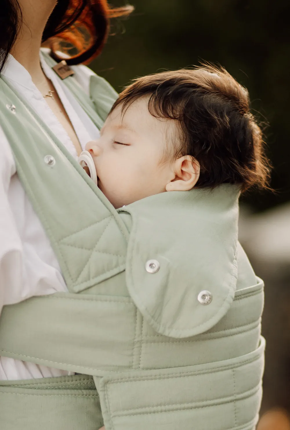 Nahaufnahme: schlafendes Baby in der Marsupi Breeze Babytrage Pistachio mit Schnuller