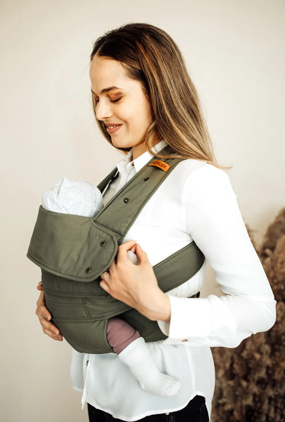 Frau trägt Baby in der Marsupi Classic 2 Babytrage Olivgrün (Olive), Seitenansicht im Studio