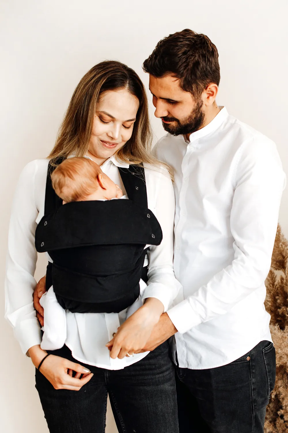 Paar schaut liebevoll auf Baby in Marsupi Classic Babytrage Schwarz.
